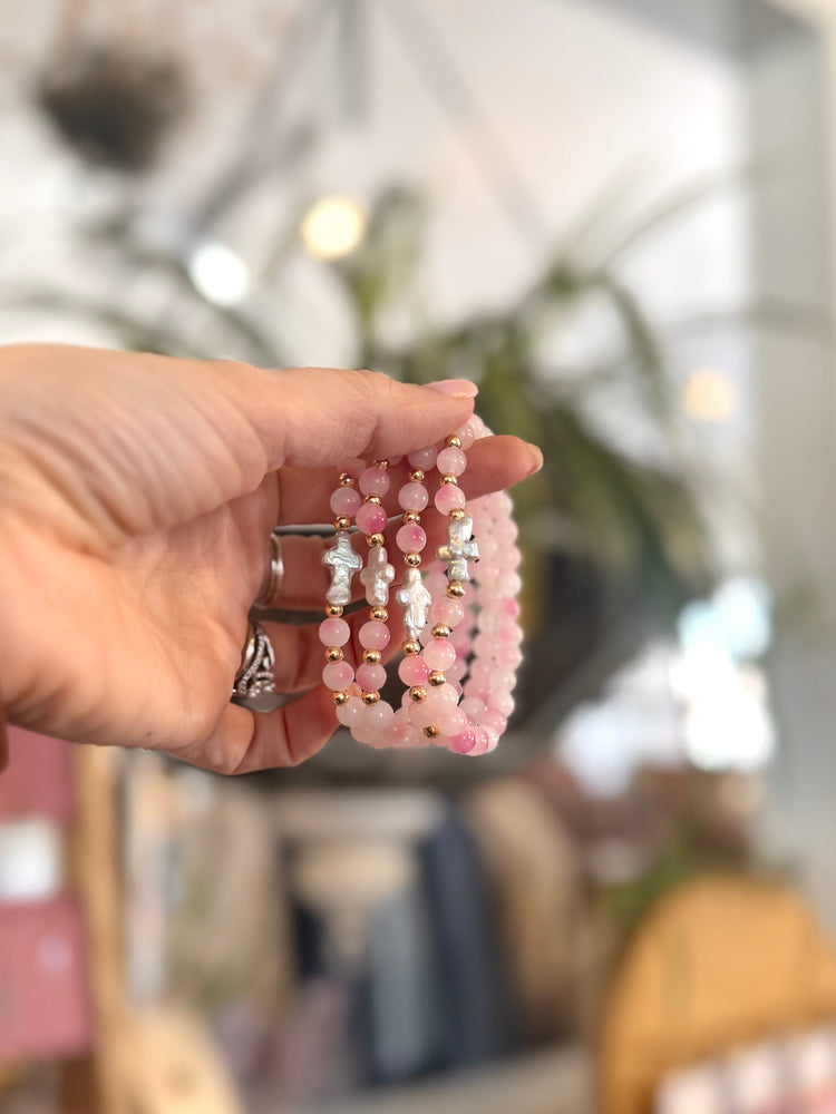 Hand holding a set of pink beaded bracelets with a blurred background